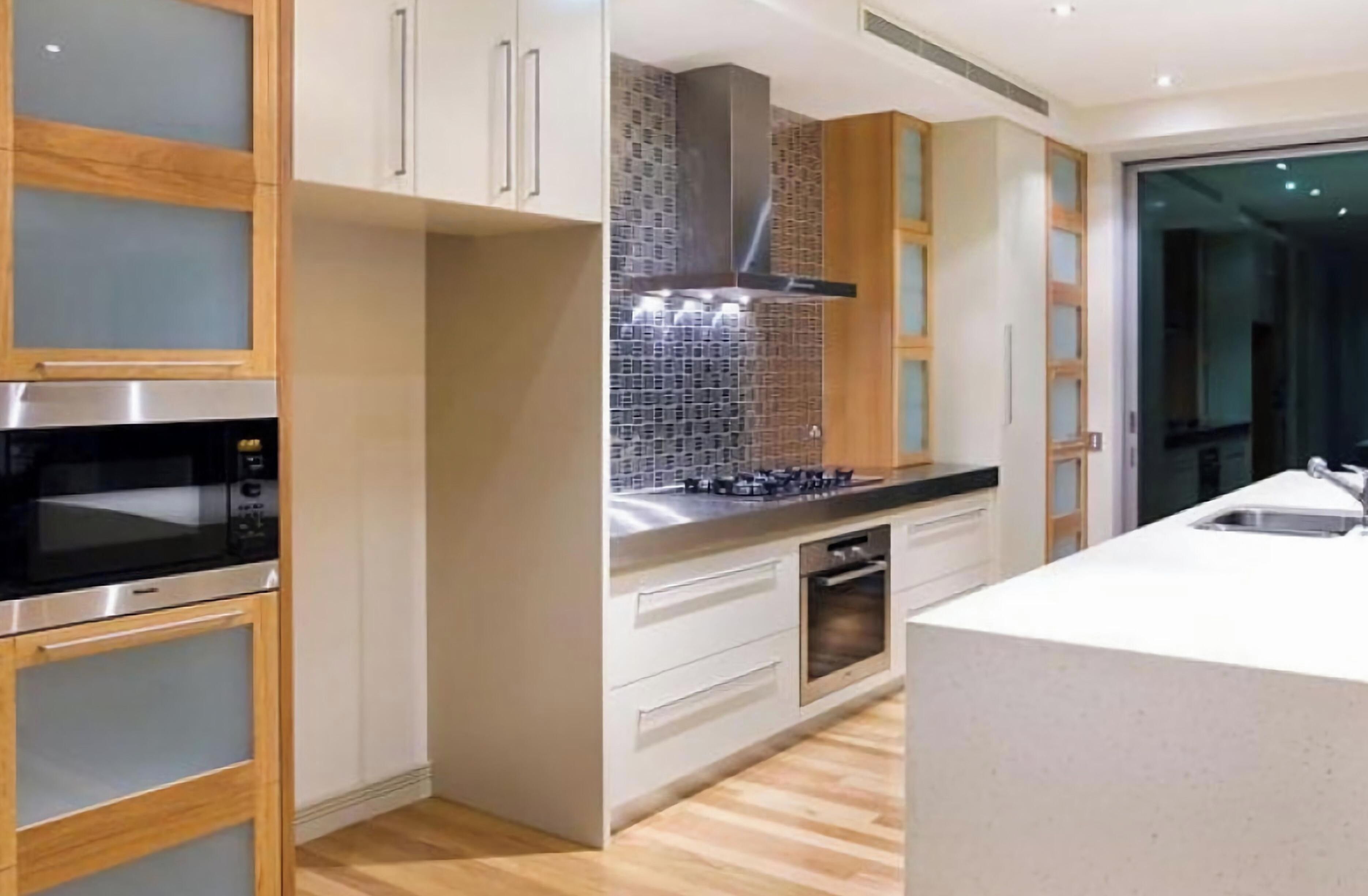 A modern kitchen with stainless steel appliances, wooden cabinets, and a tiled backsplash.