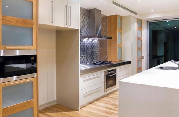 A modern kitchen with stainless steel appliances, wooden cabinets, and a tiled backsplash.