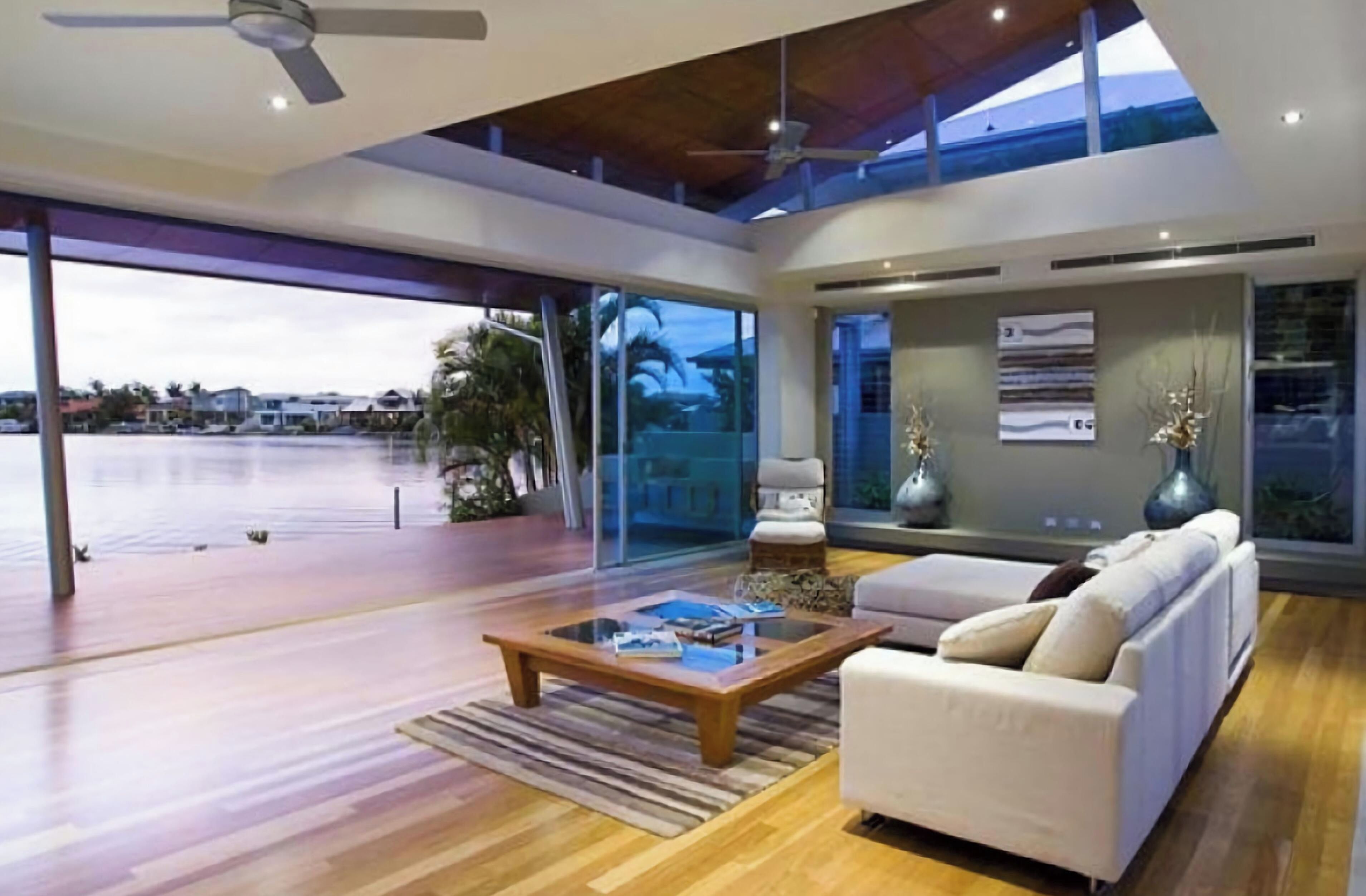 A spacious living area with a large glass door leading to a balcony, a wooden coffee table, and a white sofa.