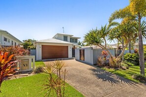 A modern house with a garage, a driveway, and a well-maintained lawn with various plants.