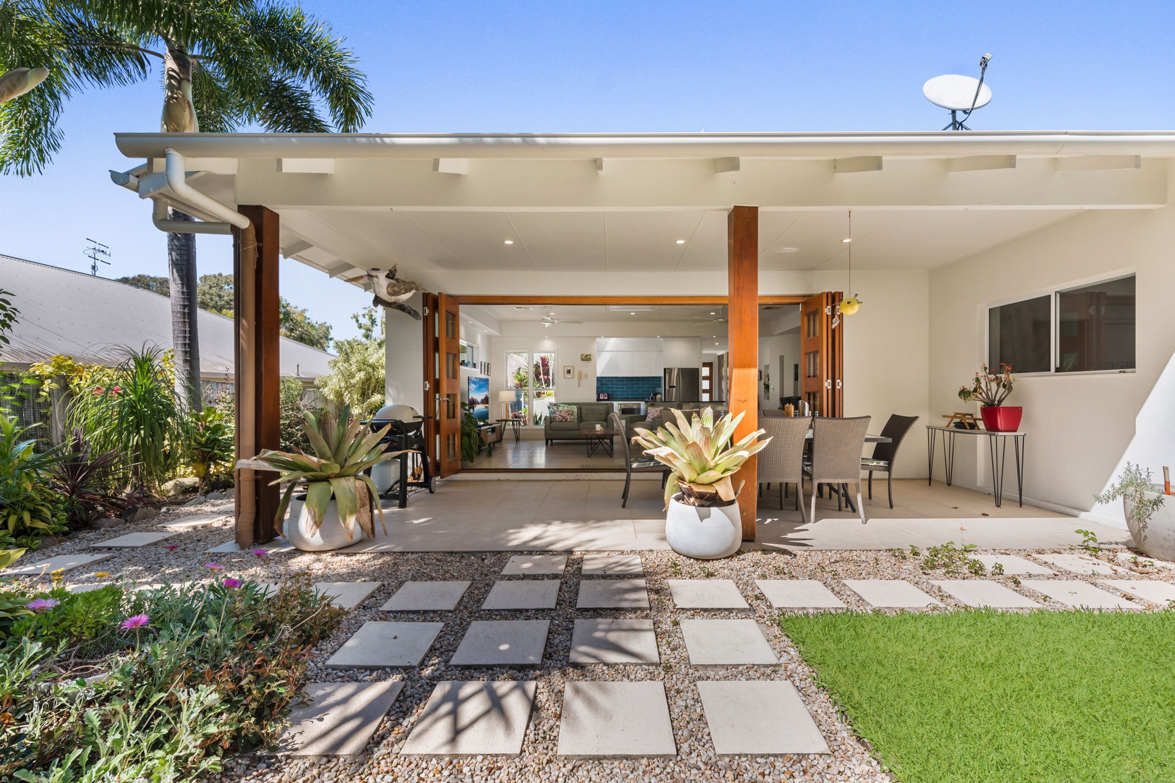 Ein modernes Haus mit überdachter Terrasse, Sitzgelegenheiten im Freien und Blick ins Innere.