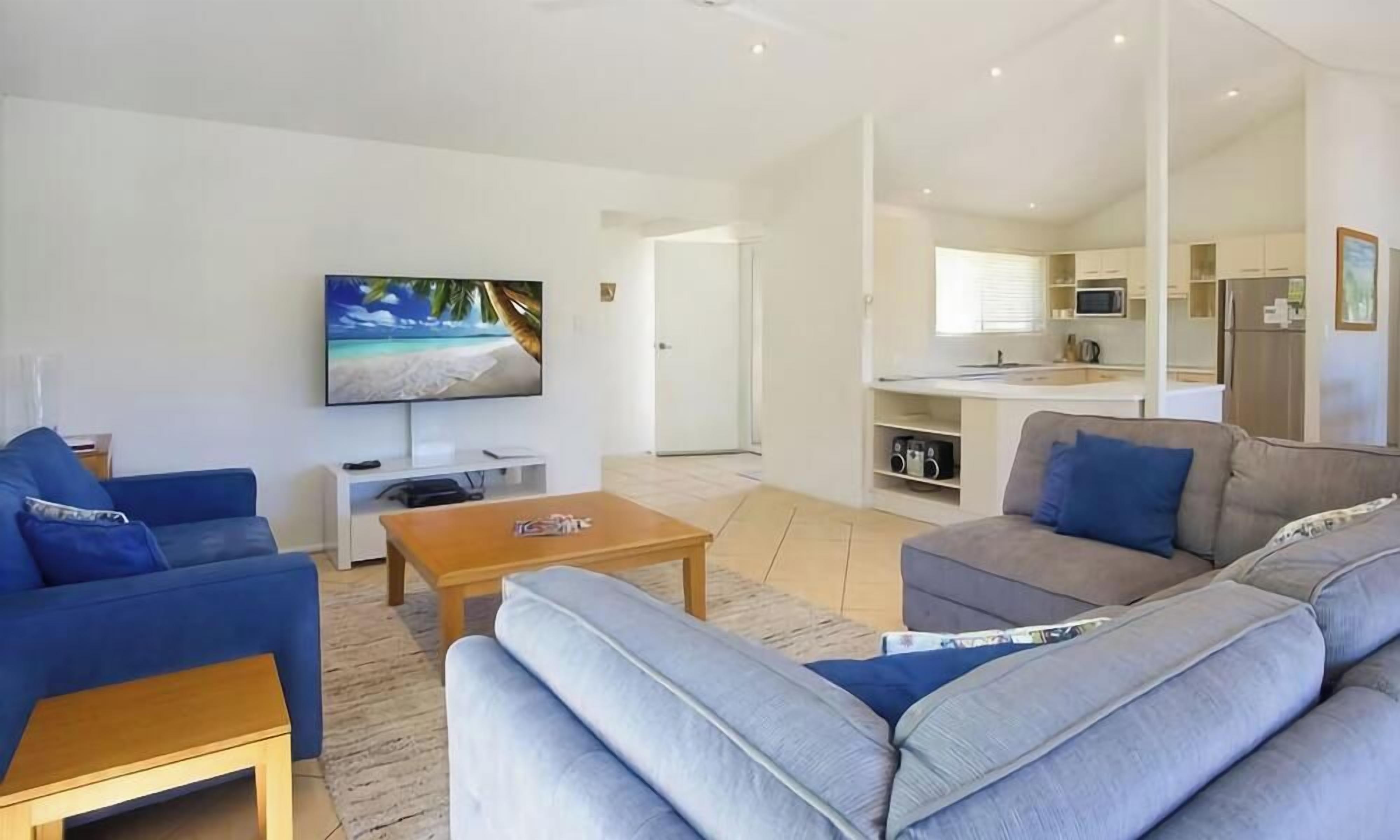 A modern living room with a flat-screen TV, a sofa, and a coffee table.