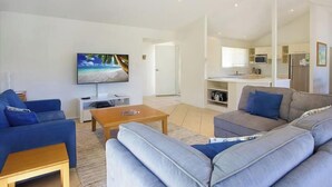 Ett modernt vardagsrum med en platt-TV, en soffa och ett soffbord.