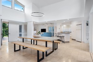 Una cucina moderna con isola centrale, zona pranzo con tavolo e panche in legno, e interni luminosi con luce naturale.