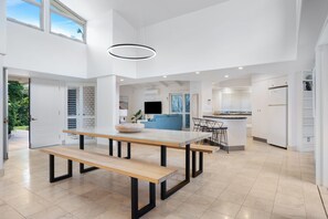 A modern kitchen with a dining area, a built-in bench, and a large window.