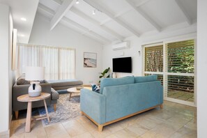 Un salon moderne avec un canapé, une table basse et un téléviseur.