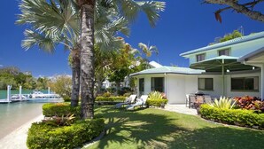 A resort with a pool, palm trees, and a covered outdoor seating area. - Wyuna Drive 53 (Noosaville)