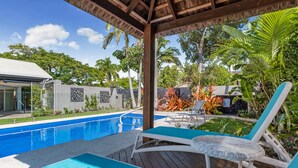 Ein Poolbereich mit Liegestühlen und einer Pergola.