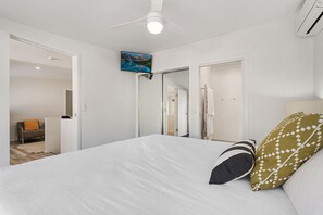 A modern bedroom with a large bed, a ceiling fan, and a mounted TV.