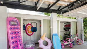 Ein Lagerraum mit verschiedenen Gegenständen, darunter ein pinkfarbener Schwimmreifen, ein blauer Schwimmreifen, ein pinkfarbener Ring und ein Kinderfahrrad.