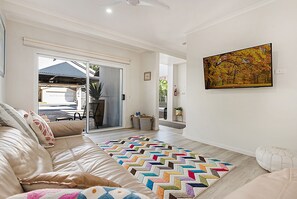 A living room with a sofa, a colorful rug, a television, and a door leading to an outdoor area.