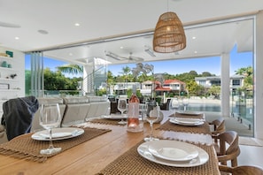 Un coin repas avec une table dressée pour quatre personnes, une bouteille de vin et une vue sur un quartier résidentiel avec des maisons et de la verdure.