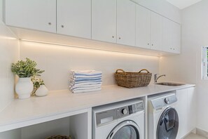 Un área de lavandería con lavadora, secadora y una encimera con toallas y una cesta.