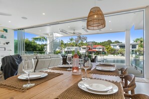 Un espace repas offrant une vue sur une piscine et sur des maisons en arrière-plan.