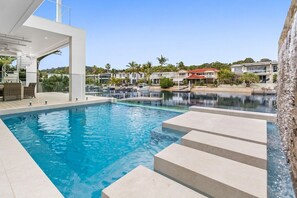 A swimming pool with steps leading into it, surrounded by modern buildings and palm trees. - Key Court 17 (Noosa Heads)