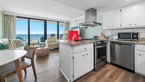 Une cuisine moderne avec des armoires blanches, des appareils en acier inoxydable et une vue sur la plage.