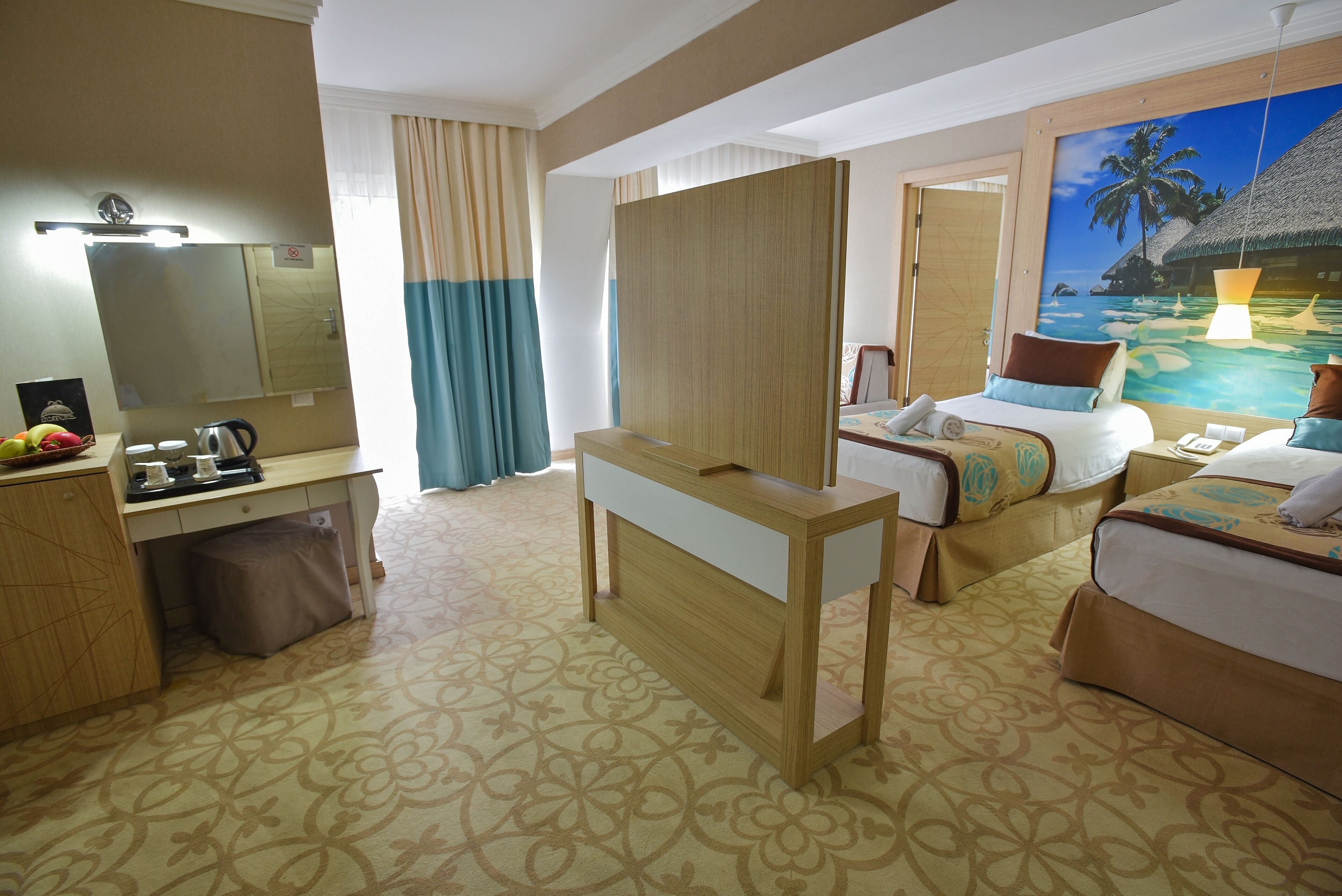A hotel room with a bed, a desk, a mirror, a wardrobe, and a painting of a tropical beach.