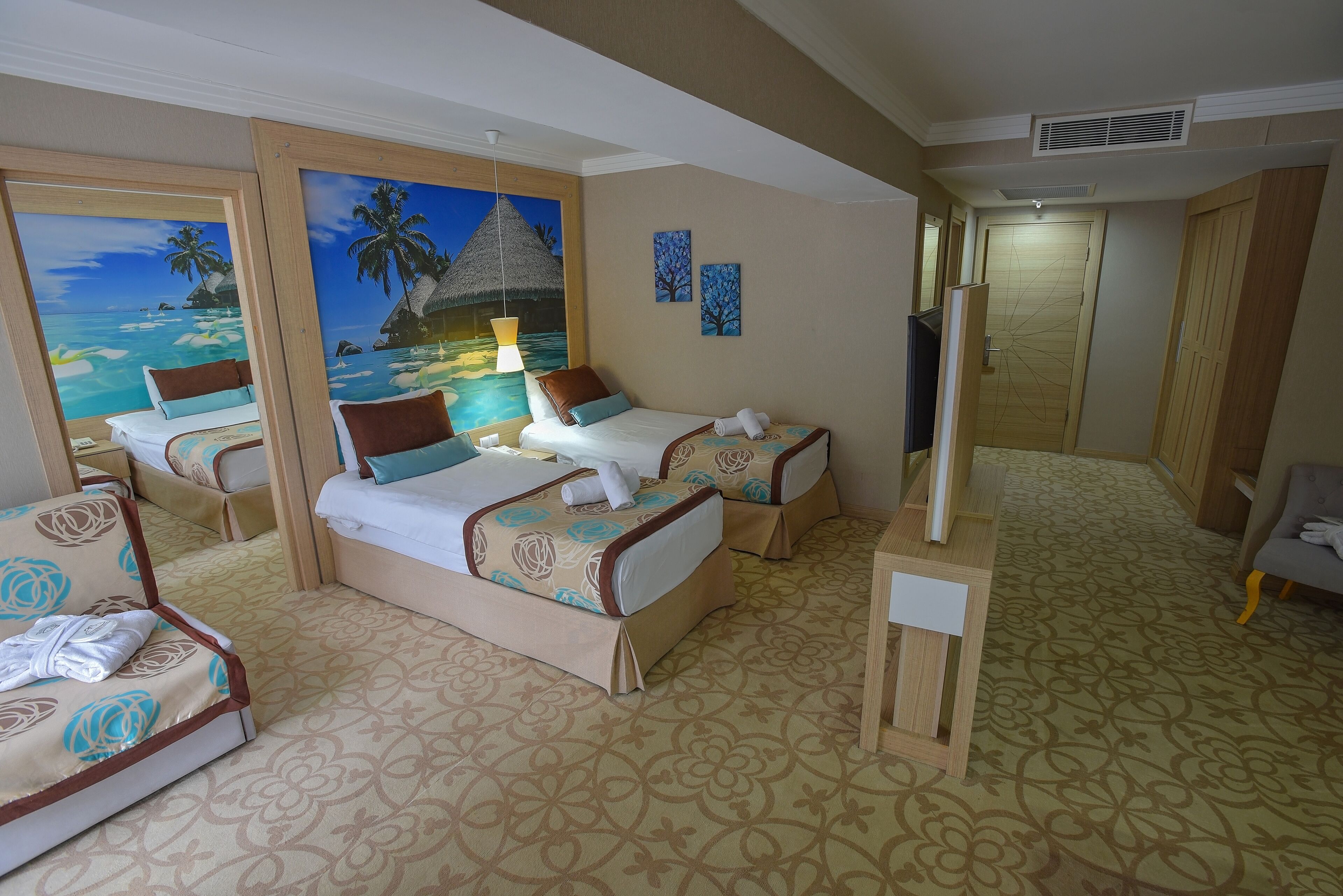A hotel room with two beds, a TV, and a painting of a beach scene.