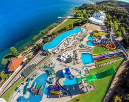 Vista aérea de un resort con múltiples piscinas, parque acuático y un edificio grande, probablemente para comidas o eventos.