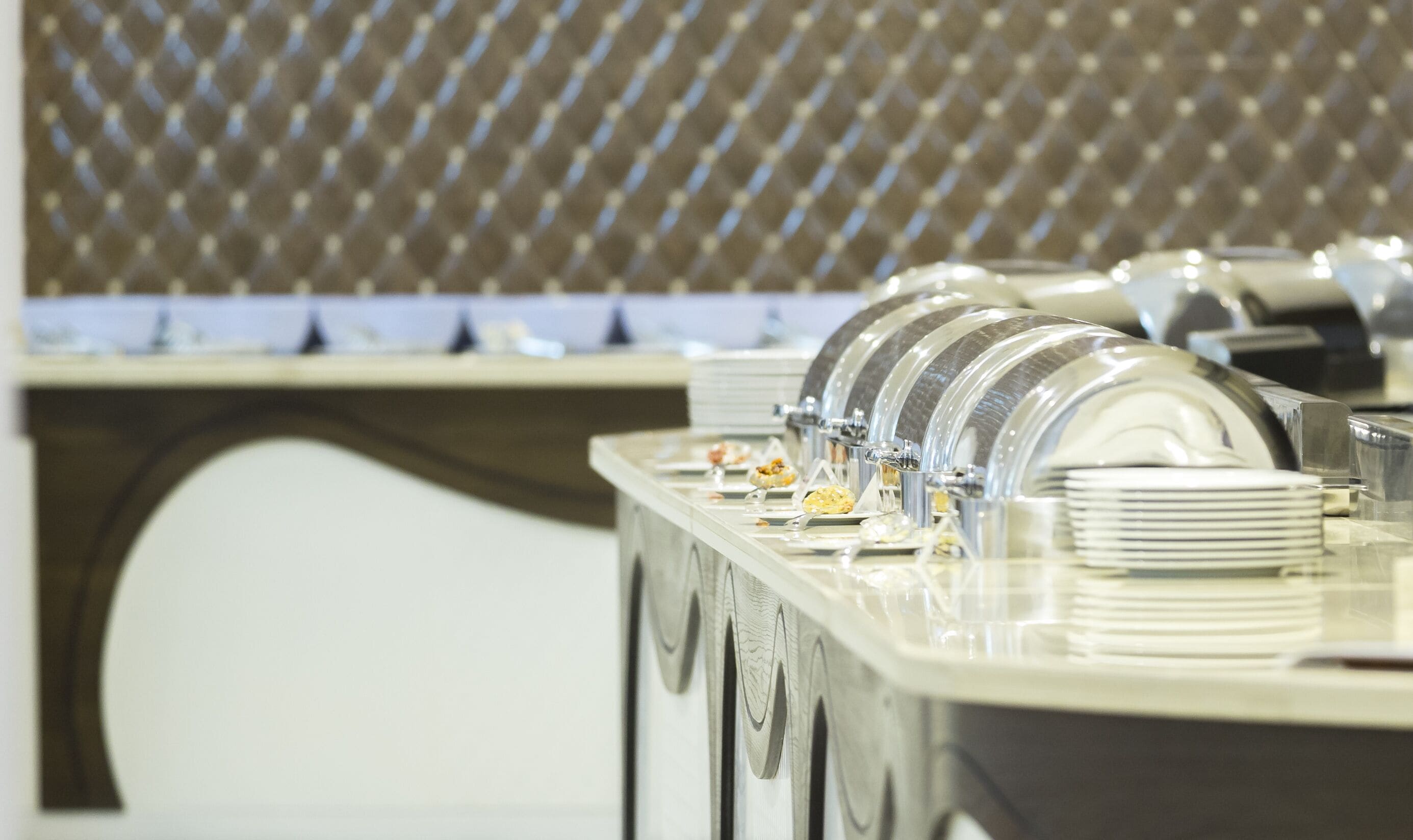 A buffet setup with multiple serving stations, clear glassware, and stacked plates.