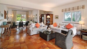 Ein Wohnzimmer mit einer Sofagarnitur, einem Couchtisch und einem Essbereich mit Stühlen und einem Tisch.