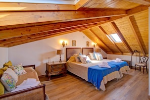 A bedroom with two beds, wooden beams, a skylight, and a nightstand with a lamp. - Vacation Home 'Villa Oliva AL - T4' with Mountain Views, Pool, Sunny Terrace, Wi-Fi & A/C (Moncarapacho)
