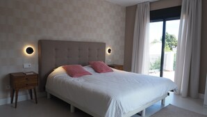 Un dormitorio con una cama grande, dos mesitas de noche, una lámpara de pared y vistas al exterior.