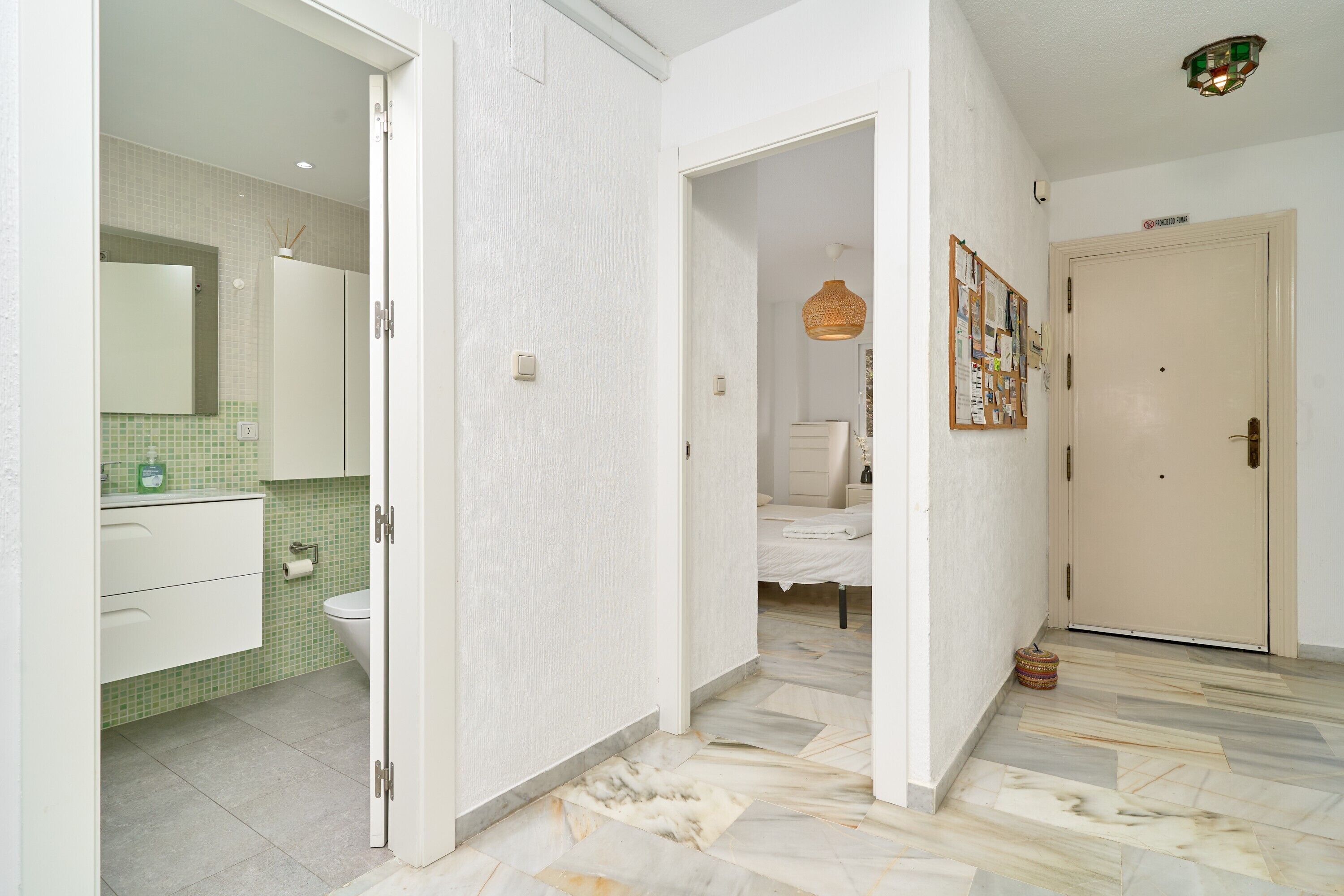 Een gang met aan de linkerkant een badkamer, in het midden een slaapkamer en aan de rechterkant een deur.