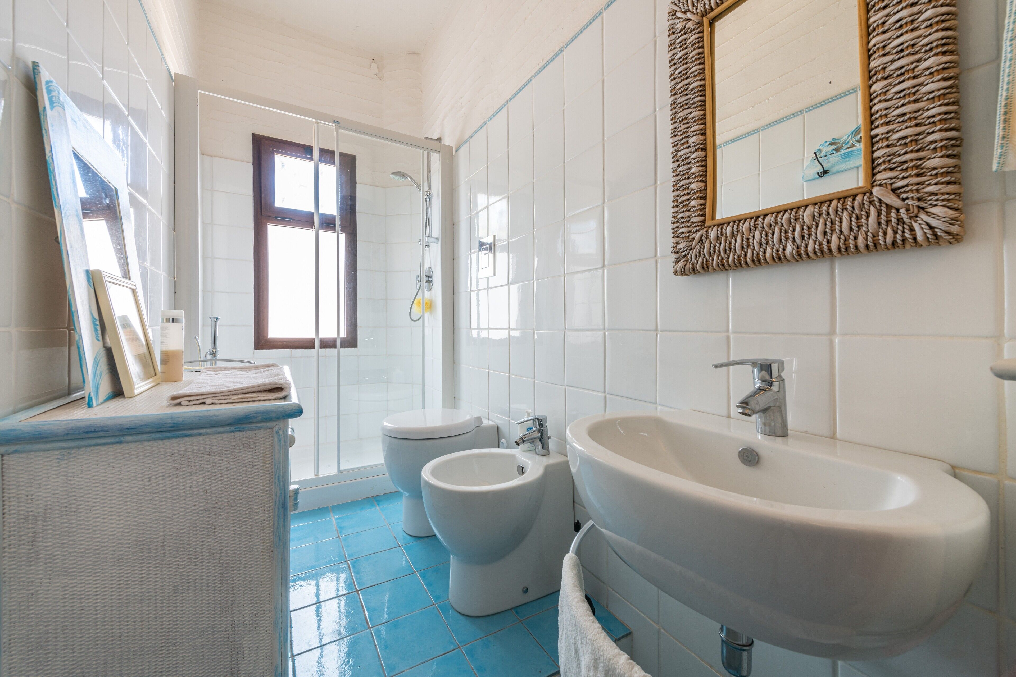 A bathroom with a shower, toilet, bidet, and sink.