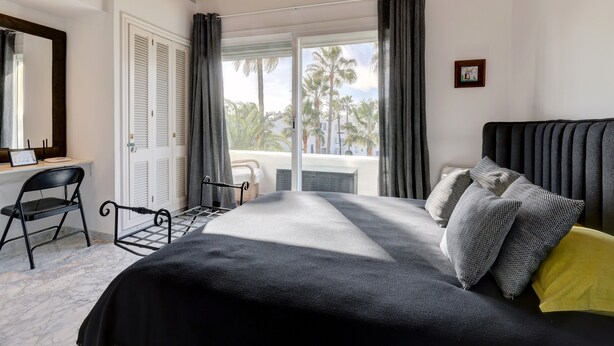Un dormitorio con cama, escritorio, silla y ventana con cortinas.