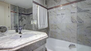 Une salle de bain avec un lavabo en marbre, une baignoire et une douche.