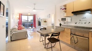 Una cucina moderna con zona pranzo, ventilatore a soffitto e vista attraverso una porta in vetro.