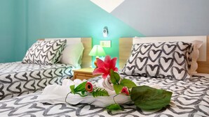 Una camera d'albergo con un letto, cuscini, un comodino, una lampada e un elemento decorativo a parete.
