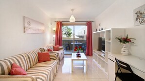 Un soggiorno con divano, tavolino, televisore e balcone con vista.