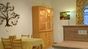 Un comedor con una mesa dispuesta para cuatro, un aparador de madera con puertas de cristal y una lámpara fijada a la pared.