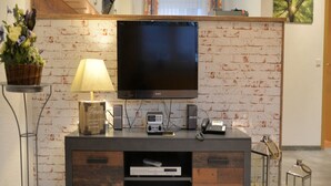 Una sala de estar moderna con un televisor de pantalla plana, una lámpara, un altavoz y una cesta decorativa.