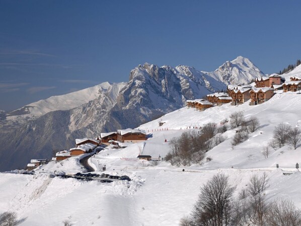 A snow-covered mountain village with wooden buildings and a ski slope.