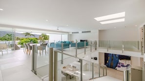 A modern interior with a balcony, seating area, and a staircase. - Lido Grande | Swim-out Apartment @ Pool Resort (PORT DOUGLAS)