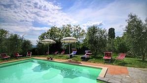 A swimming pool with lounge chairs and umbrellas. - Belvilla by OYO Villa Lucignano (Lucignano)