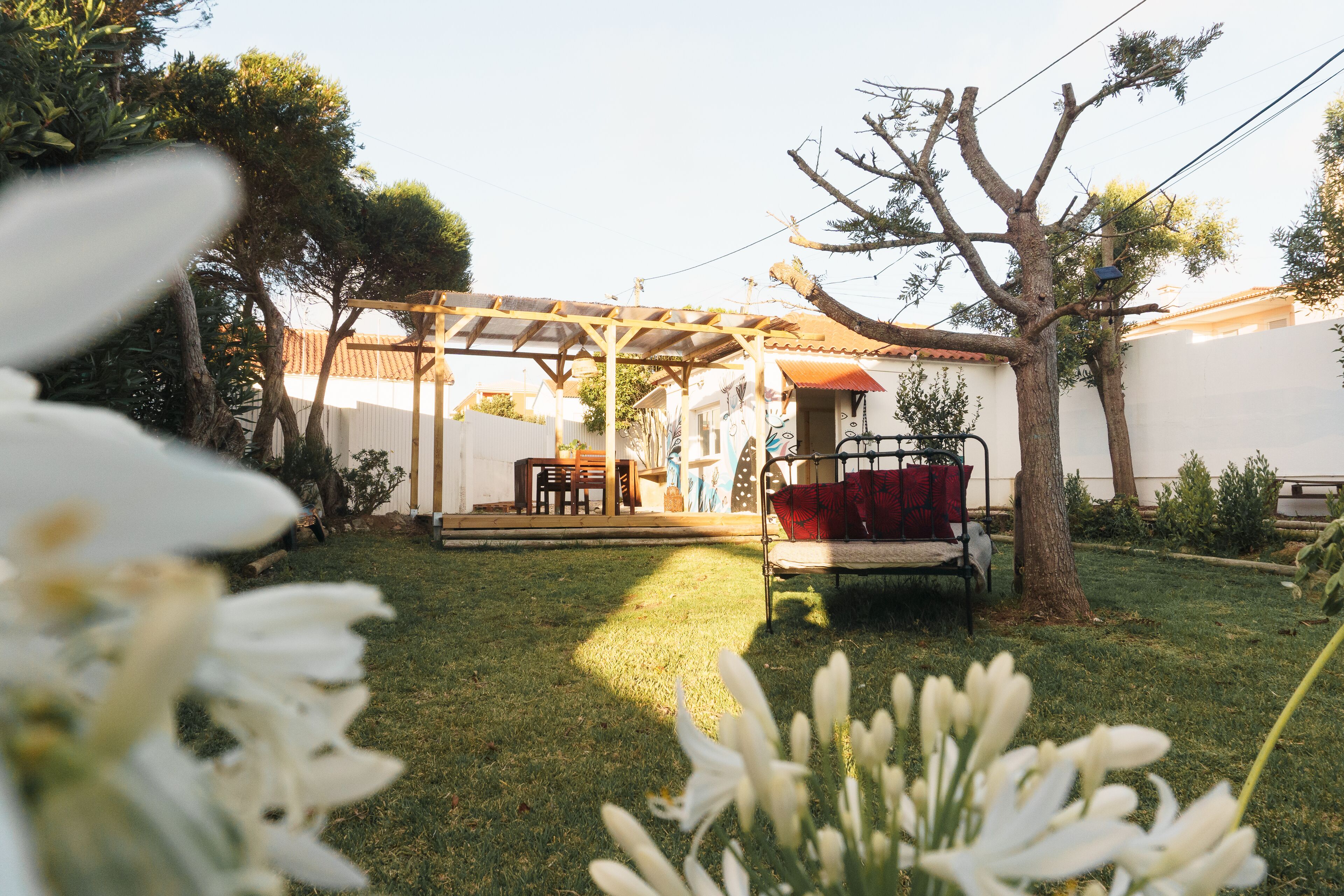 Un espacio de patio cubierto con una pérgola de madera, un banco y una mesa.