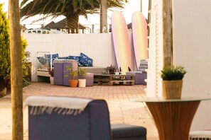 A patio area with a seating arrangement, surfboards, and potted plants.