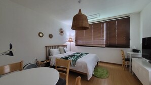 A bedroom with a bed, bedside table, lamp, and a TV. - Jeju Eltzutown Pension (Jeju City)