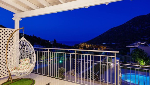 Un balcon agrémenté d’un fauteuil suspendu, une piscine et une vue sur un paysage montagneux.