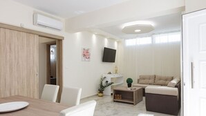 Un salon moderne comprenant un coin repas, un téléviseur à écran plat fixé au mur et un canapé.