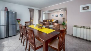 A dining area with a wooden table, chairs, a refrigerator, and a radiator. - Vacation home with pool - a paradise for families (Žminj)