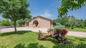 A two-story house with a stone facade, a central arched entrance, and a well-maintained lawn with potted plants. - Vacation home with pool - a paradise for families (Žminj)