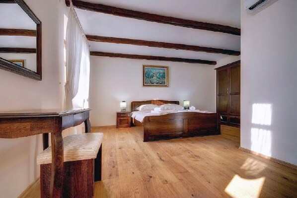A bedroom with a wooden bed, a nightstand, a mirror, and a painting on the wall.