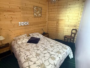 A wooden room with a bed, a chair, and a nightstand.