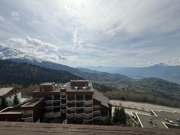 A multi-story building with a flat roof, surrounded by mountainous terrain and a clear sky.