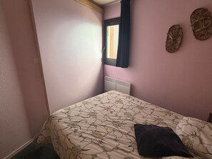 A bedroom with a bed, a window with curtains, and a wall with a decorative plate.